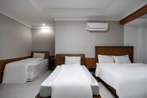 A hotel room with two single beds, a wooden headboard, a bedside table, and an air conditioning unit. - Prima Hotel (Seosan)