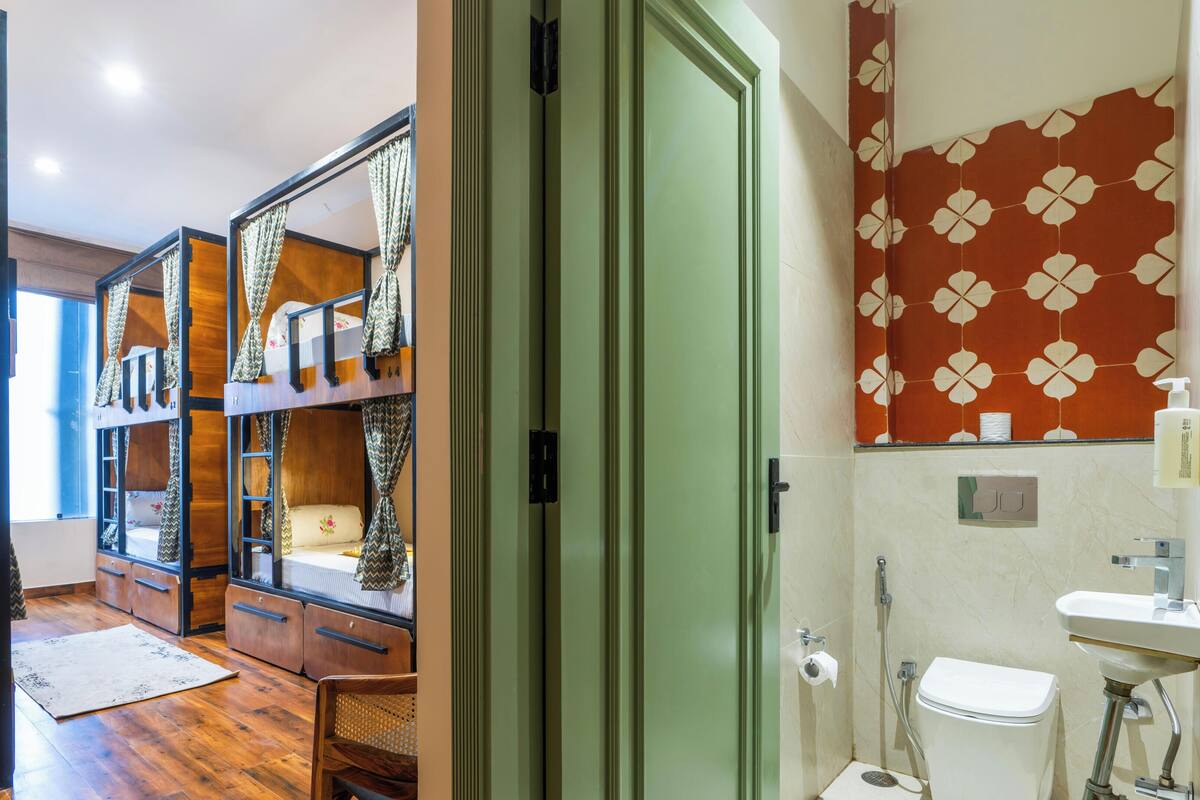 Una habitación con literas, baño con inodoro y lavamanos, y ducha.