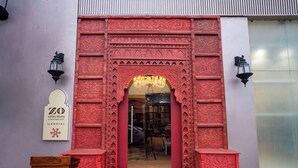 Entrada de un hotel boutique con intrincados grabados rojos, una araña y un cartel.