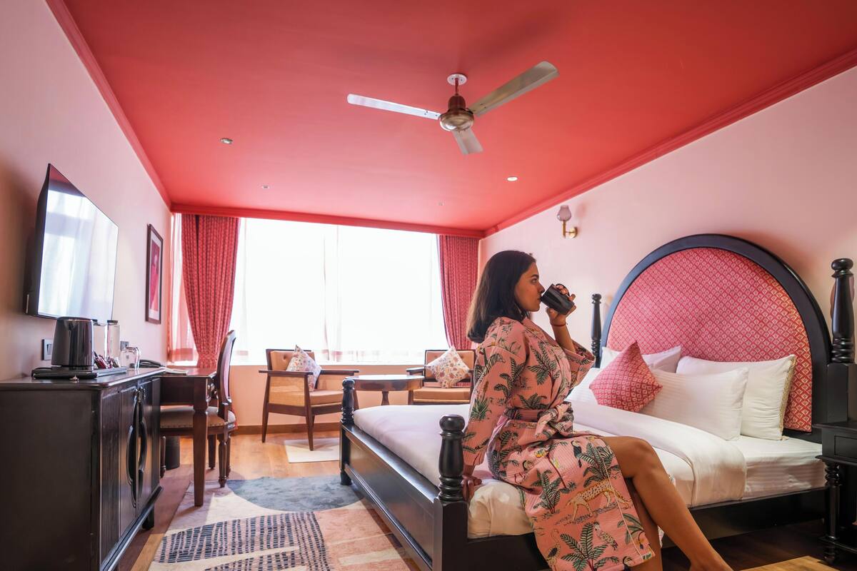 Una habitación con cama, escritorio, silla, ventilador de techo y ventana con cortinas.