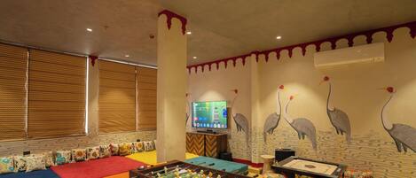 A room with a foosball table, a television, and a wall mural.