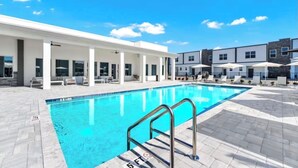 Una piscina con acqua cristallina, circondata da lettini e ombrelloni, e una zona relax coperta con colonne.