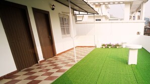 Een binnentuin met kunstgras, een geruit vloert en potplanten.