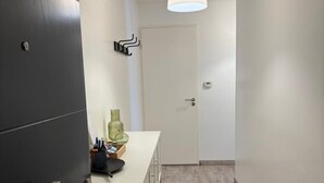 Um corredor com luminária moderna, uma porta e um balcão com objetos.