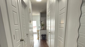 A hallway with white doors and brown wooden flooring.