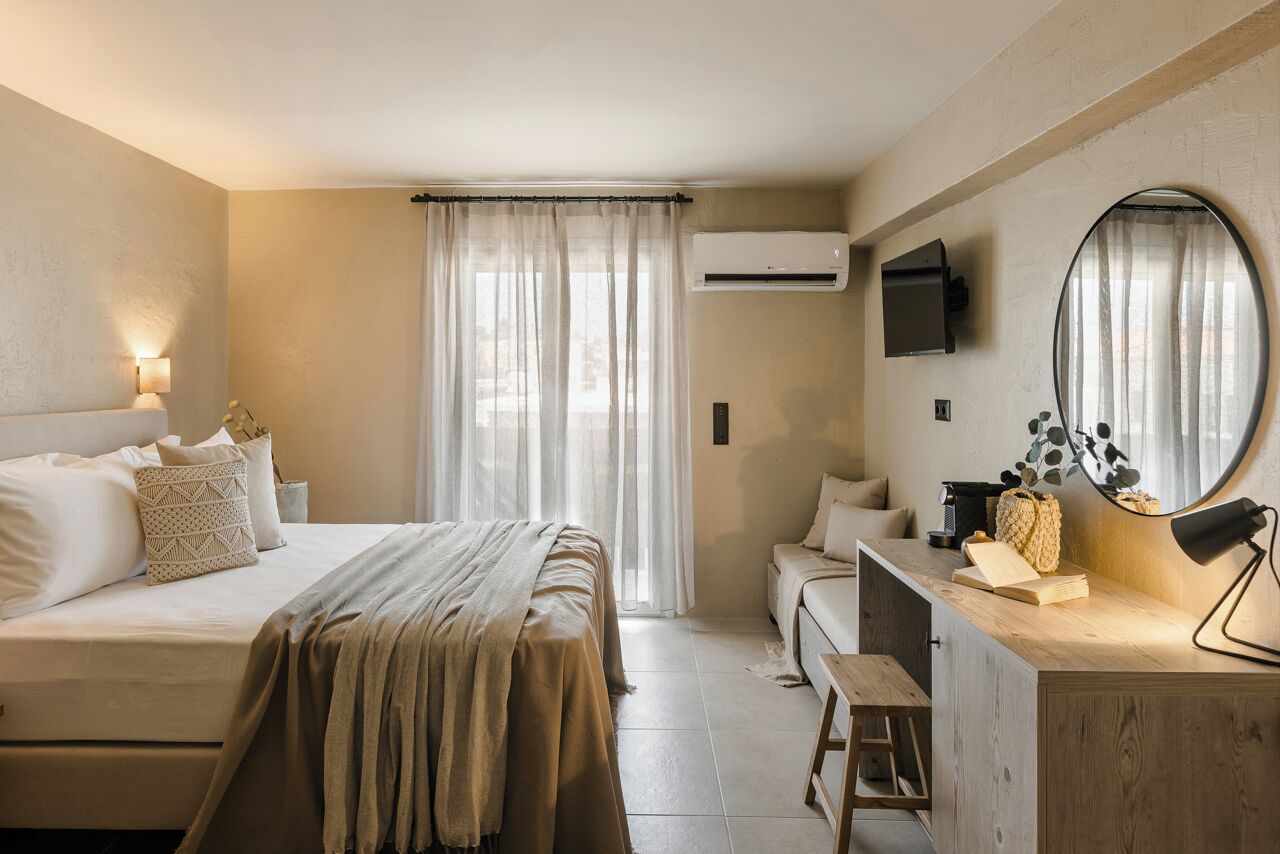 Un dormitorio con cama, mesita de noche, escritorio, silla y aire acondicionado.