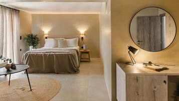 A modern bedroom with a large bed, bedside lamps, a round mirror, and a small table with a lamp.