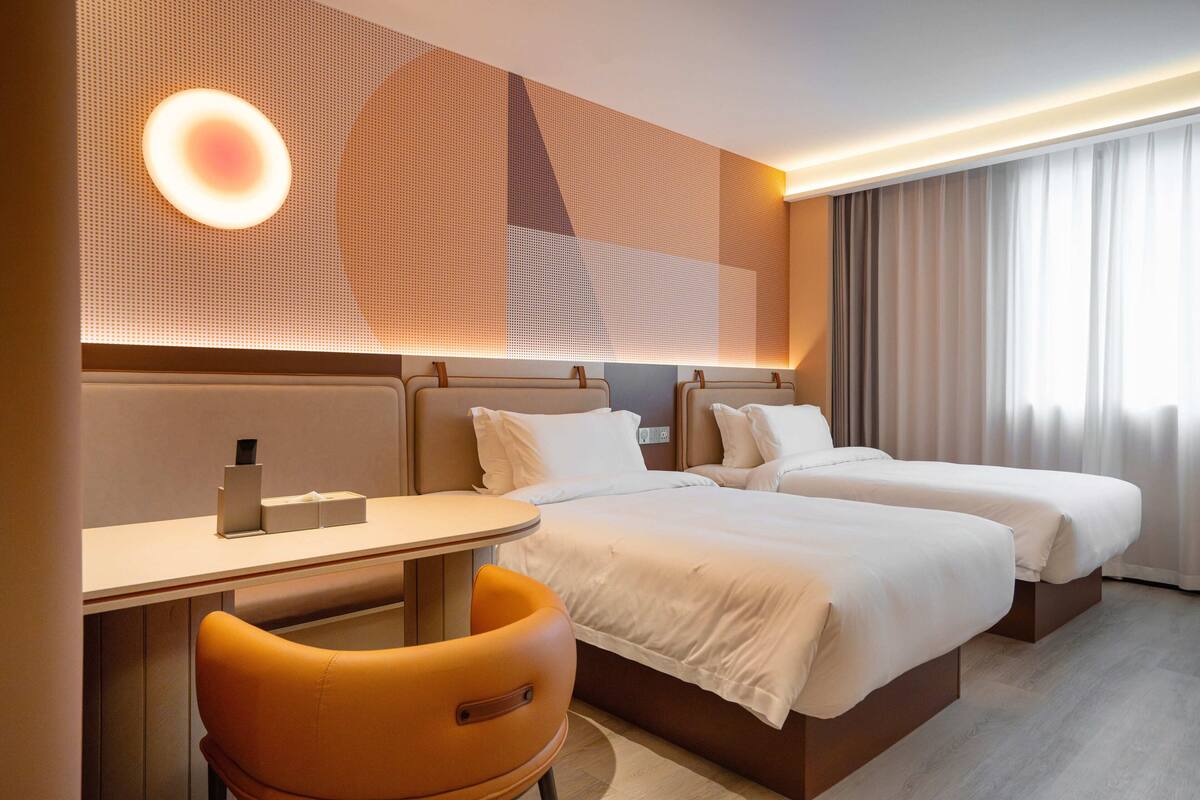 Ein Hotelzimmer mit zwei Betten, einem Schreibtisch und einem Stuhl.