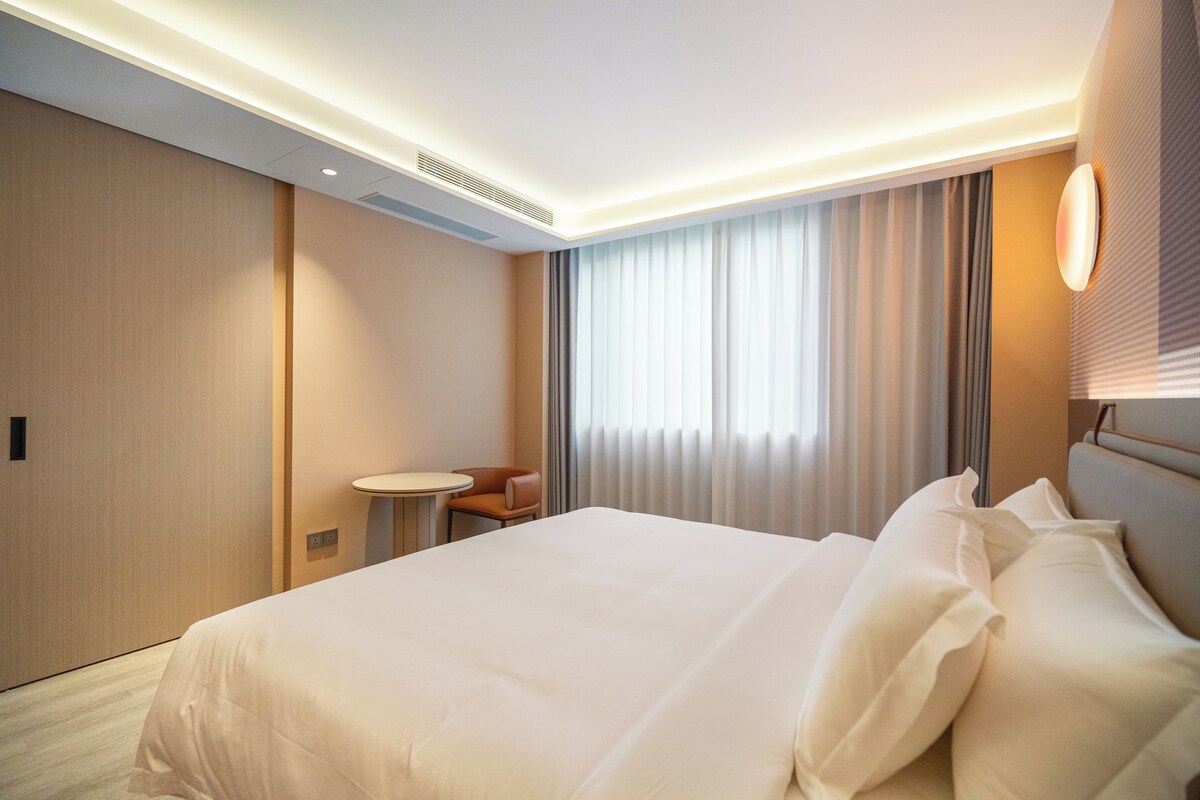 Een hotelkamer met een groot bed, een tafeltje en een stoel.