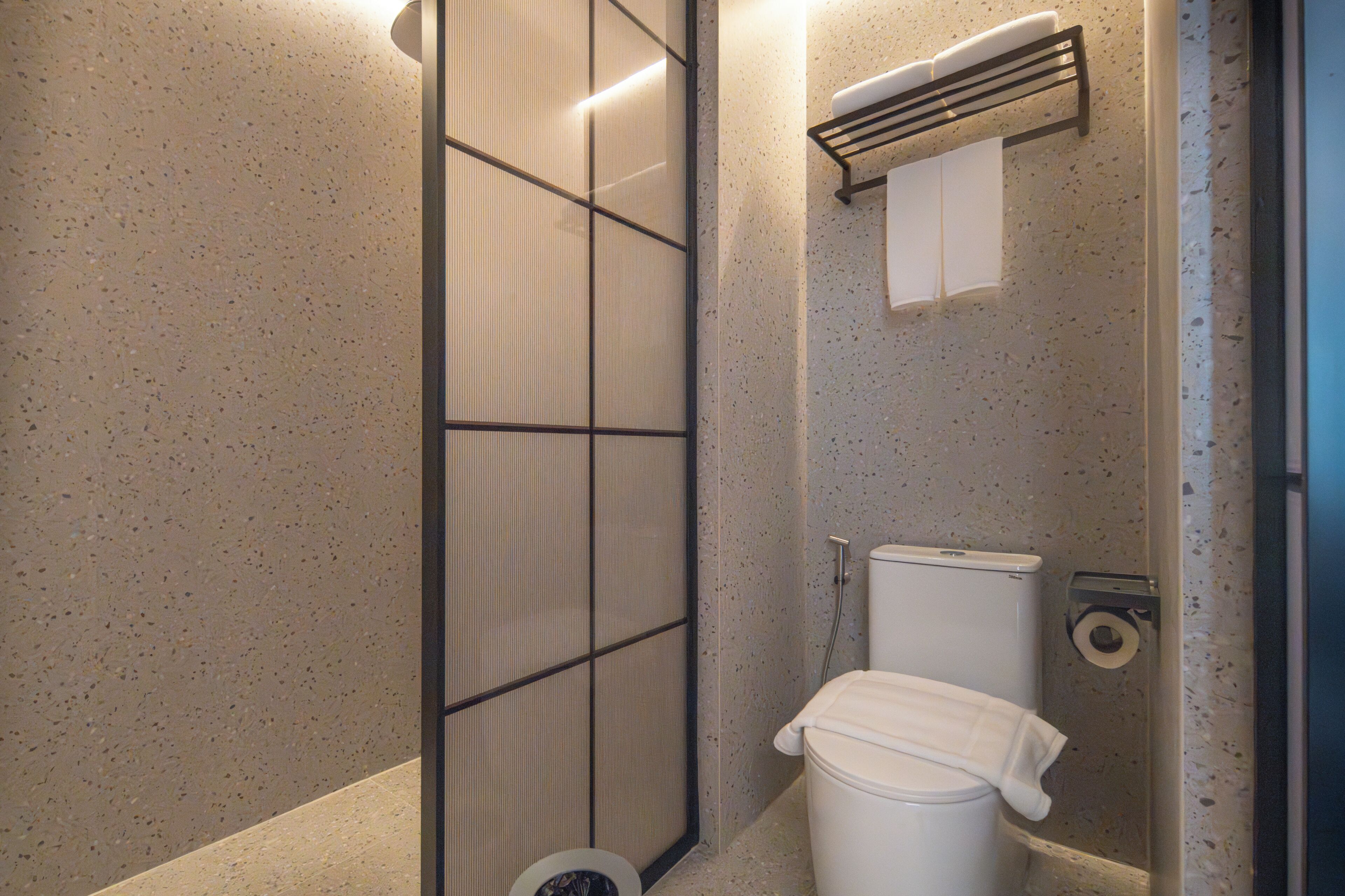 Ein Badezimmer mit Toilette, Handtuchhalter und Papierhandtuchspender.