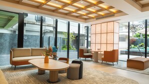Eine moderne Lobby mit einer Couch, Sesseln, einem Tisch und einer dekorativen Vase.