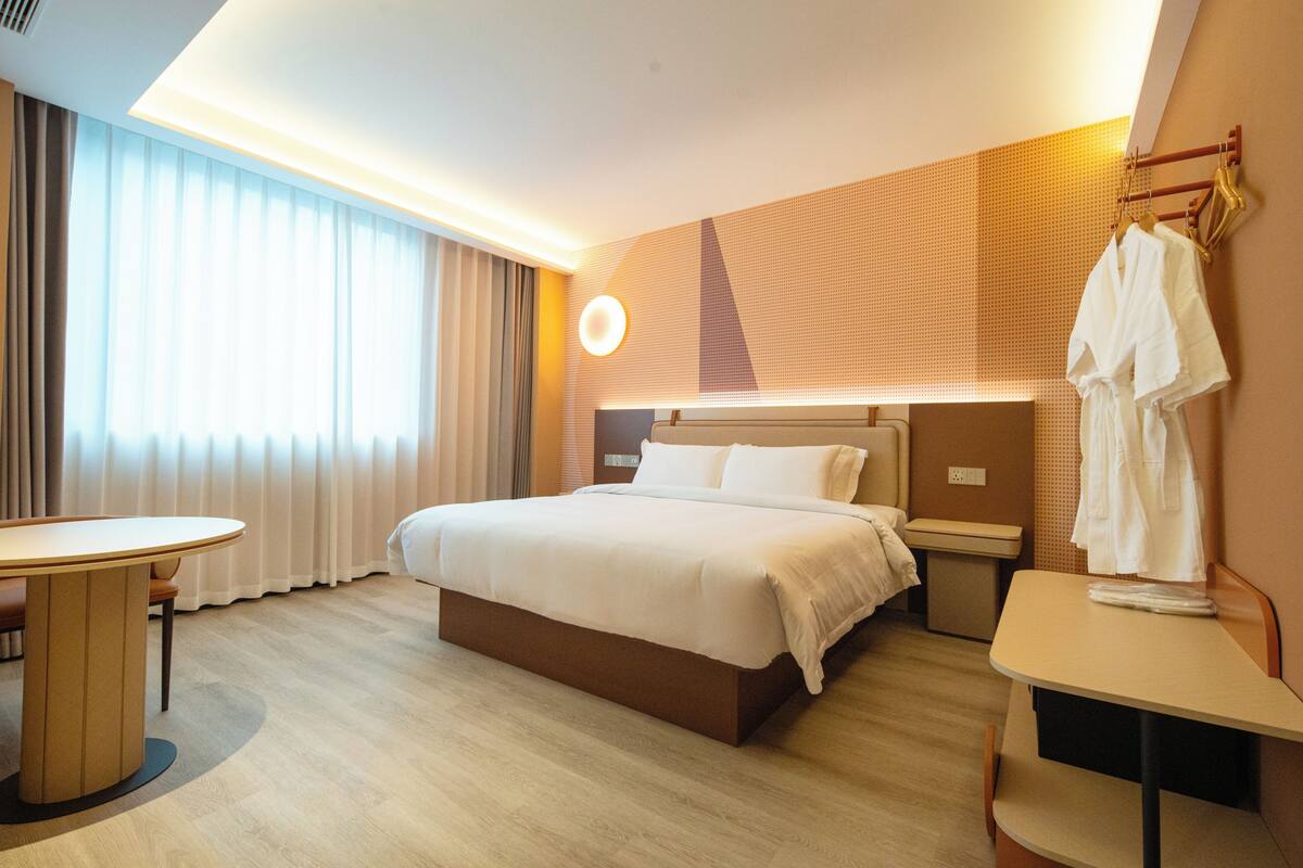 Ein Hotelzimmer mit Bett, Nachttisch und einem Tisch mit Stühlen.