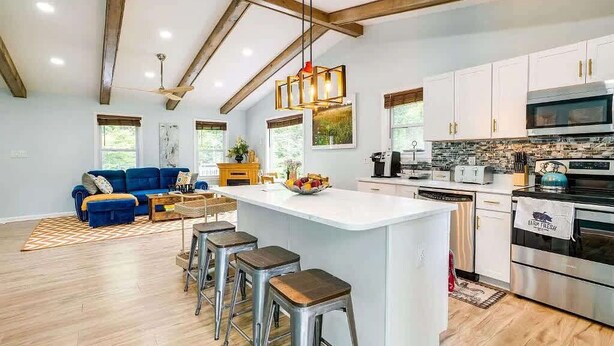 A modern kitchen with white cabinets, stainless steel appliances, and a central island with stools. - Greek Spa • Private Acreage • Stonefire pizza oven (Front Royal)
