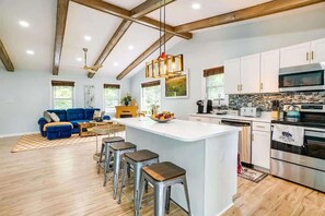 A modern kitchen with white cabinets, stainless steel appliances, and a central island with stools. - Frisbee golf • Private Acreage • Stonefire pizza (Front Royal)