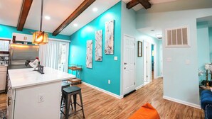 A modern kitchen with a central island, wooden beams, and a bright teal accent wall. - Greek Spa • Private Acreage • Stonefire pizza oven (Front Royal)
