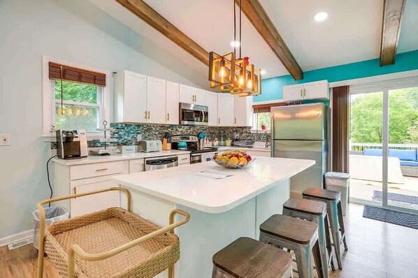 Una cocina moderna con gabinetes blancos, una isla grande y un refrigerador de acero inoxidable.