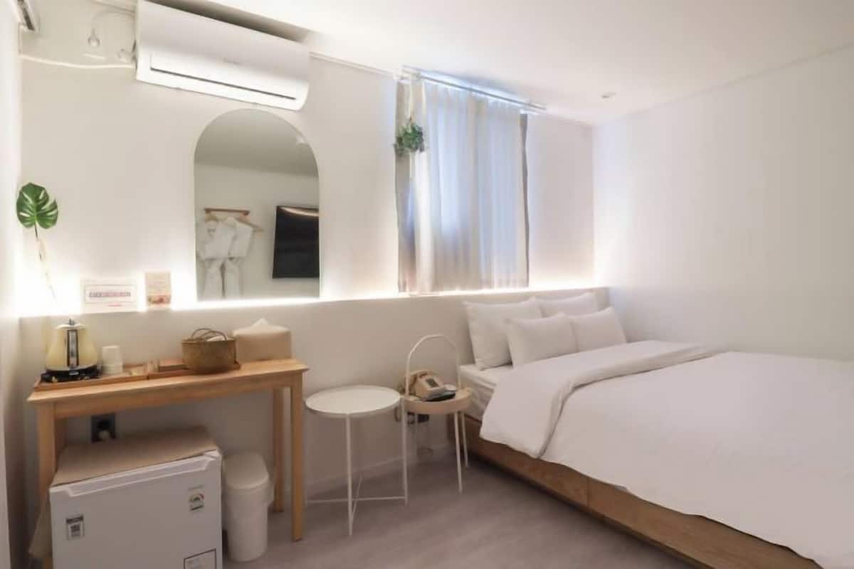Une chambre moderne comprenant un lit, un bureau, une chaise, une petite table et une fenêtre avec des rideaux.