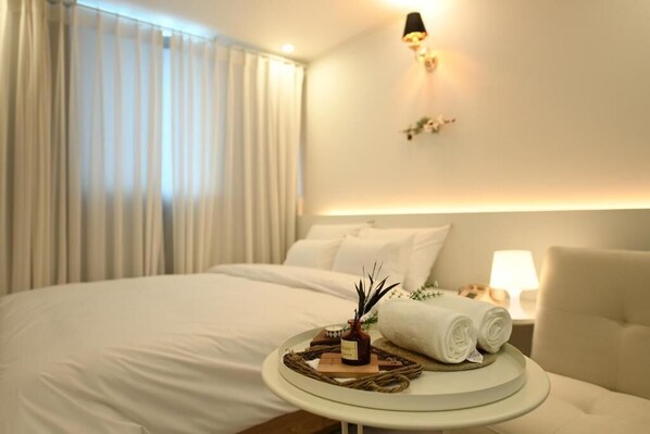 A hotel room with a neatly made bed, a bedside table with a lamp, and a wall-mounted light fixture.