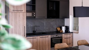 A modern kitchen with wooden cabinets, a black countertop, and a built-in oven. - Adriatic View Apartment by DuHomes (Dubrovnik)