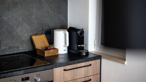 A kitchen with a black countertop, a coffee maker, a white mug, and a wooden box with a plant. - Adriatic View Apartment by DuHomes (Dubrovnik)