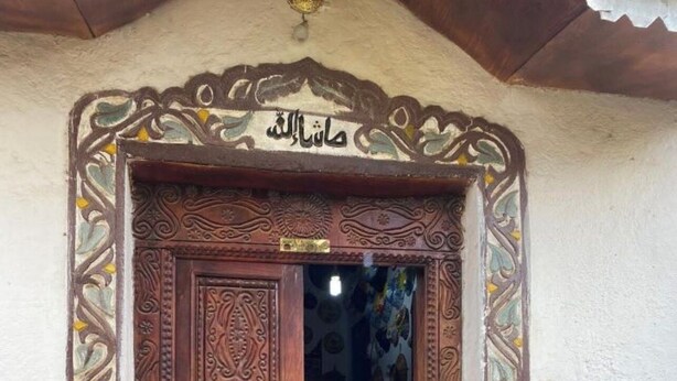A wooden door with intricate carvings and Arabic calligraphy, leading into a dimly lit interior. - Traditional Guest House  (Harar)