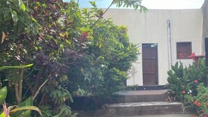 A courtyard with a concrete pathway leading to a building with a brown door and windows. - Traditional Guest House  (Harar)
