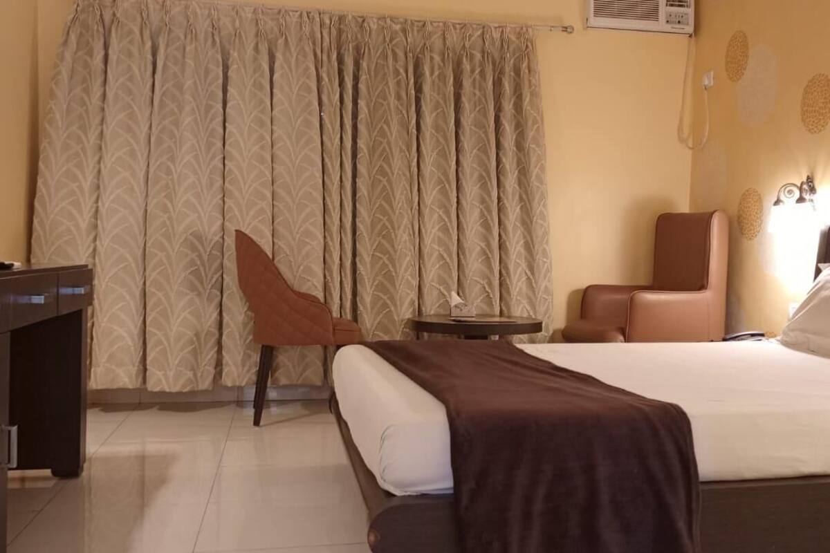 Ein Hotelzimmer mit Bett, Schreibtisch, Stuhl und kleinem Tisch.