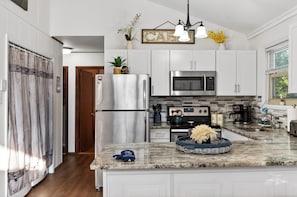 A modern kitchen with white cabinets, stainless steel appliances, and a granite countertop. - Wooded Poconos Cabin + Firepit + Large Deck + Near Big Boulder & Hickory Run (Albrightsville)