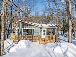 A cabin with a large glass window, wooden deck, and a snow-covered ground. - Wooded Poconos Cabin + Firepit + Large Deck + Near Big Boulder & Hickory Run (Albrightsville)