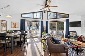 A spacious living area with a dining table, sofa, and a ceiling fan. - Wooded Poconos Cabin + Firepit + Large Deck + Near Big Boulder & Hickory Run (Albrightsville)