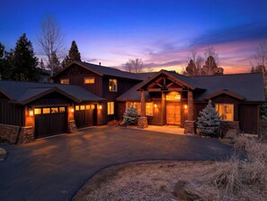 A large, multi-story wooden house with a prominent front entrance, a driveway, and a well-maintained lawn. - Sunriver Retreat + Hot Tub + Game Room + Near Golf + Trails | Mulligan Estate (Sunriver)