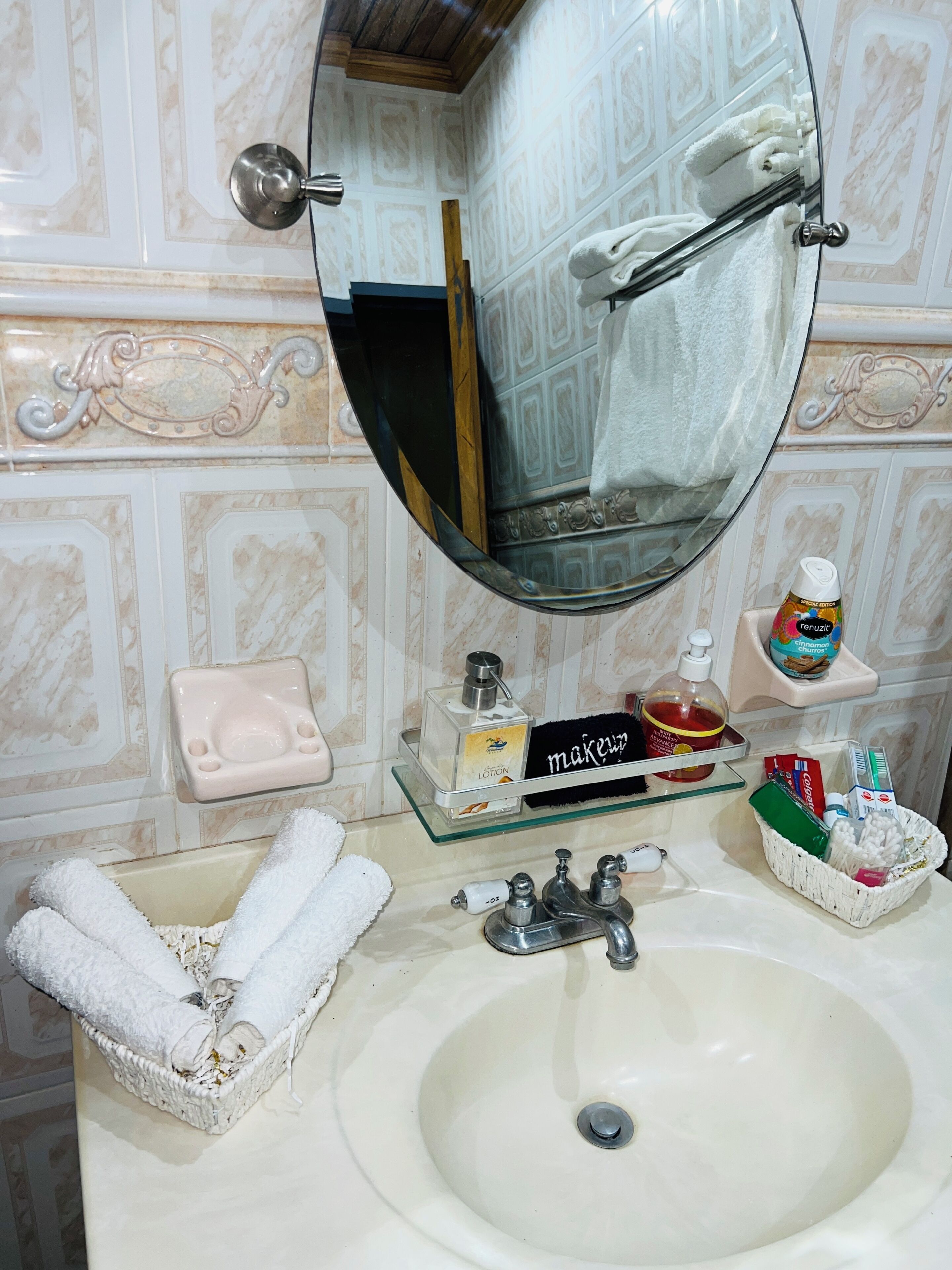 A bathroom with a sink, mirror, toiletries, and towels.