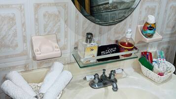 A bathroom with a sink, mirror, toiletries, and towels.