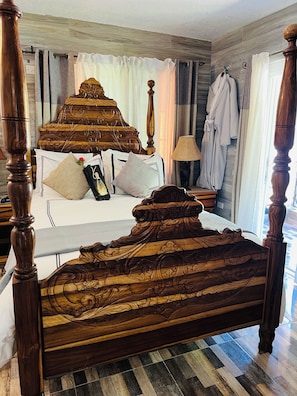 A wooden bed with intricate carvings, a bedside lamp, and a robe hanging on the wall.