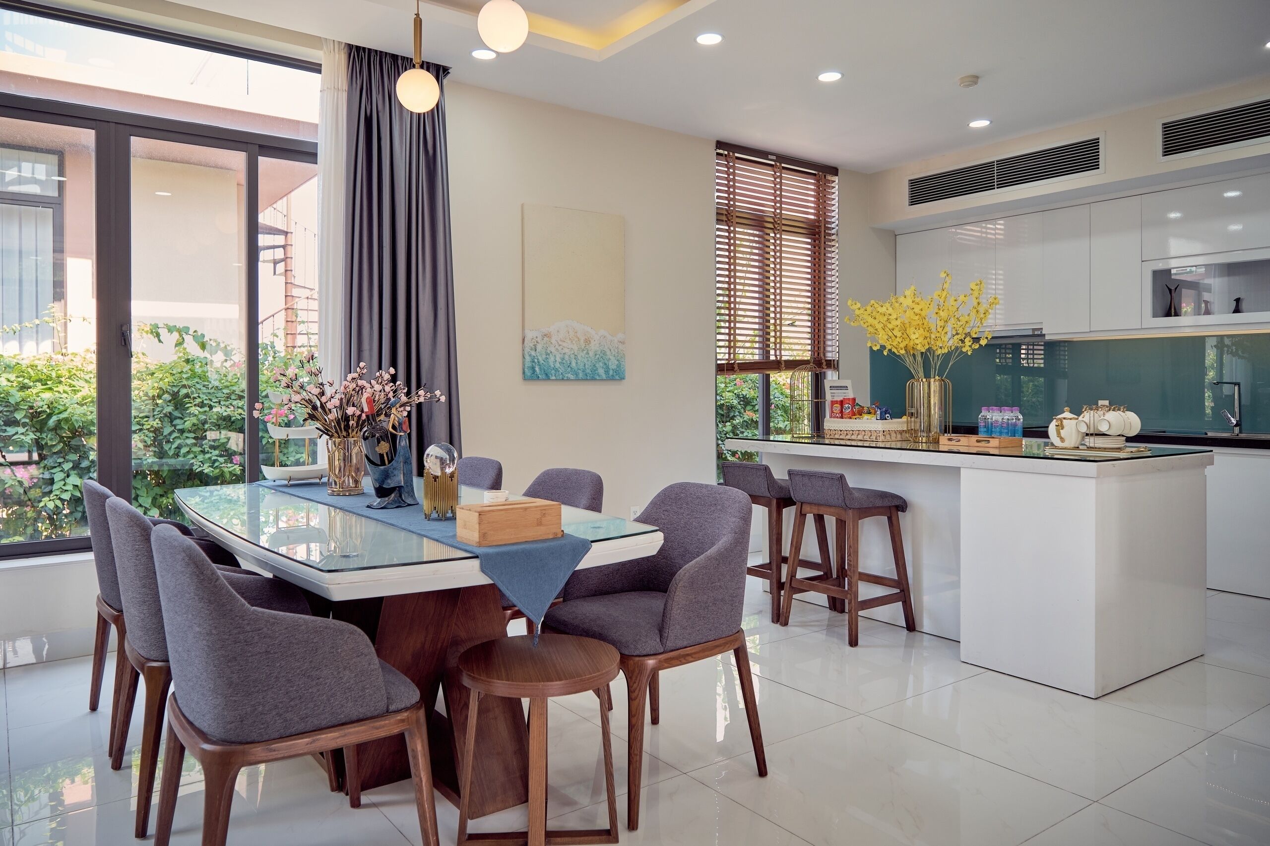 Een moderne keuken met een centraal eiland, barstoelen en een eettafel met stoelen.
