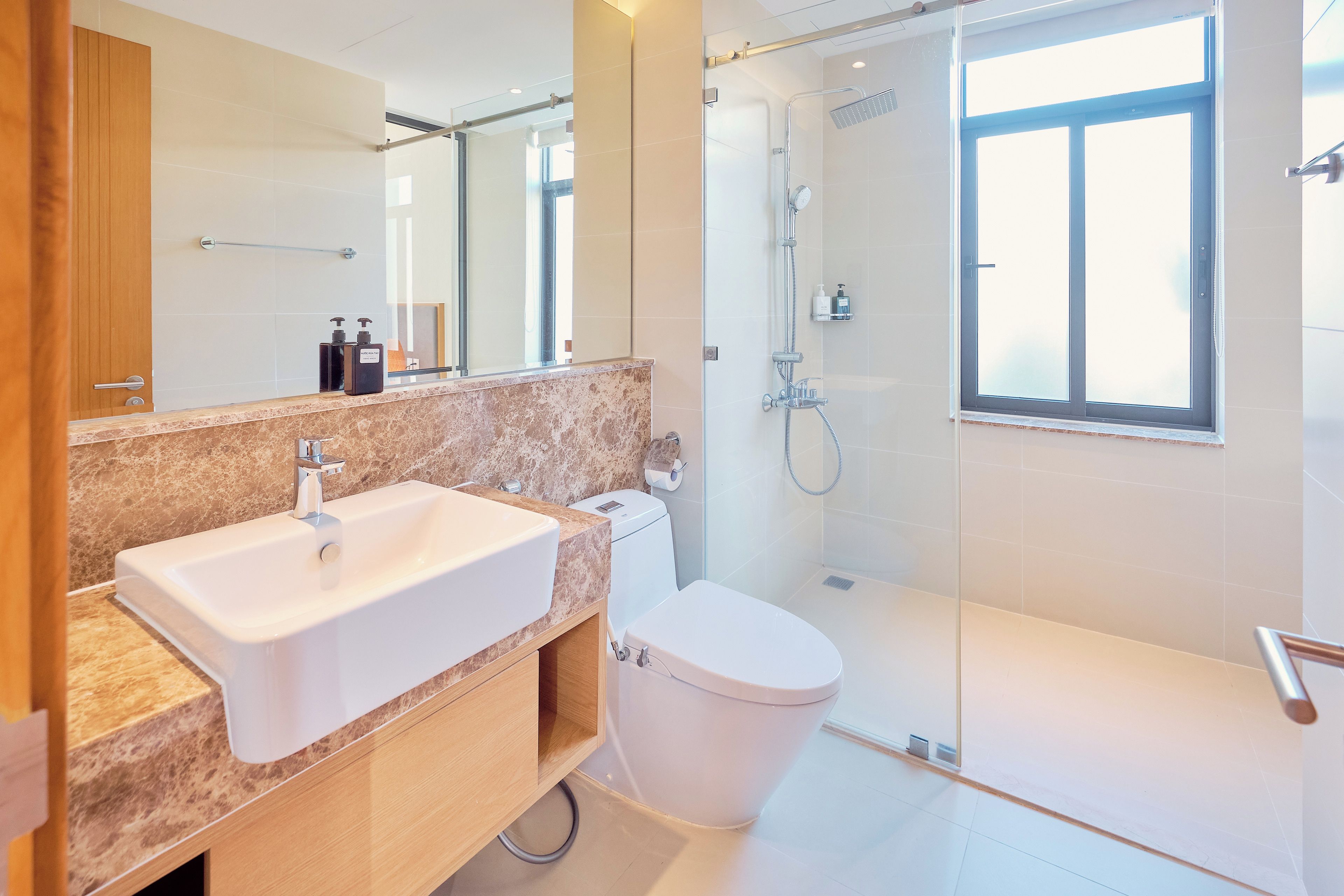 A modern bathroom with a large sink, toilet, and glass-enclosed shower area.