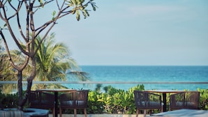 Eine Terrasse am Meer mit Korbmöbeln und Blick auf den Ozean.
