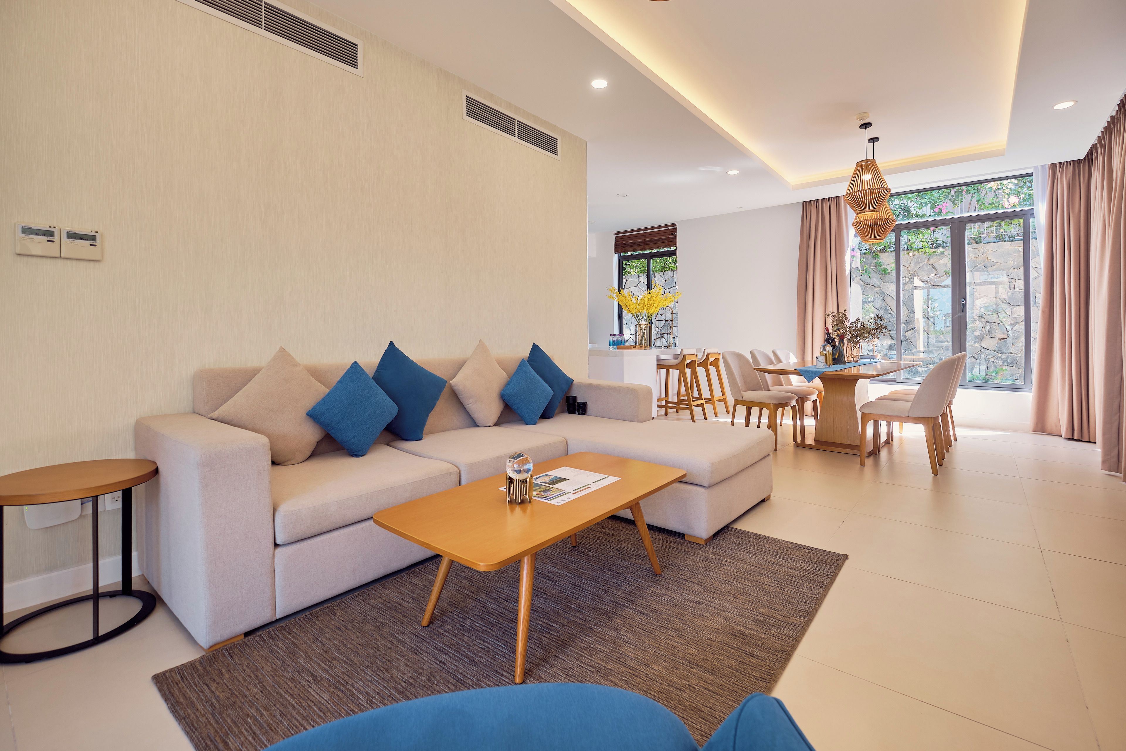 A modern living room with a sofa, coffee table, and dining area with chairs.