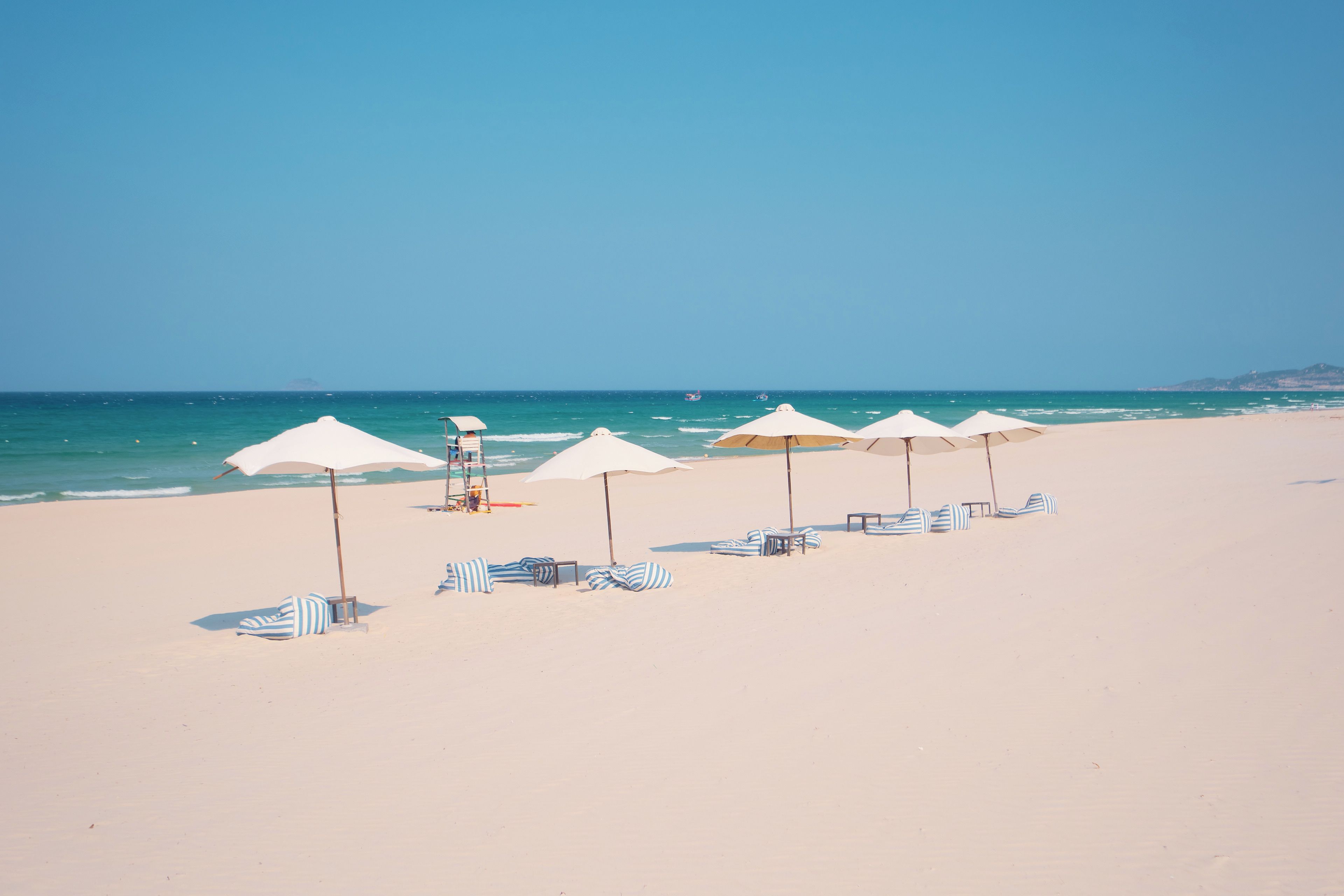 A beach with rows of sun umbrellas and lounge chairs.