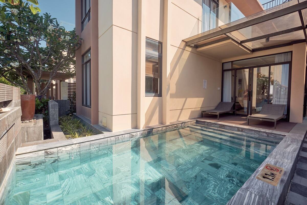 Ein modernes Gebäude mit Swimmingpool, Außenbereich zum Sitzen und einem Baum.