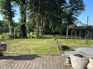 Puutarha, jossa on pergola, kivipenkkejä ja päällystetty kävelyreitti.