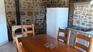 A rustic kitchen with stone walls, a wooden table, and chairs.