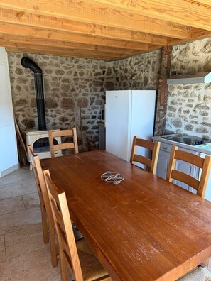 Une cuisine rustique avec des murs en pierre, une table en bois et des chaises.
