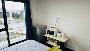 Une chambre d’hôtel avec un lit, une petite kitchenette, une fenêtre donnant sur l’extérieur et une porte.