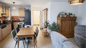 Una cocina moderna con armarios de madera, una mesa de comedor con sillas y una zona de estar con un sofá y un mueble.