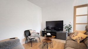 Una sala de estar moderna con televisor de pantalla plana, un sofá, una silla y una pequeña mesa de centro.