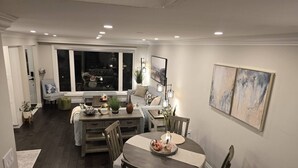 A dining area with a round table, chairs, and a view of the outdoors through a large window. - Comfortable City Home (Mississauga)