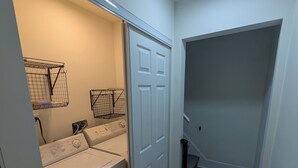 A laundry room with a washing machine, dryer, and storage racks.