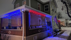 A house with a covered porch, a brick chimney, and an American flag.