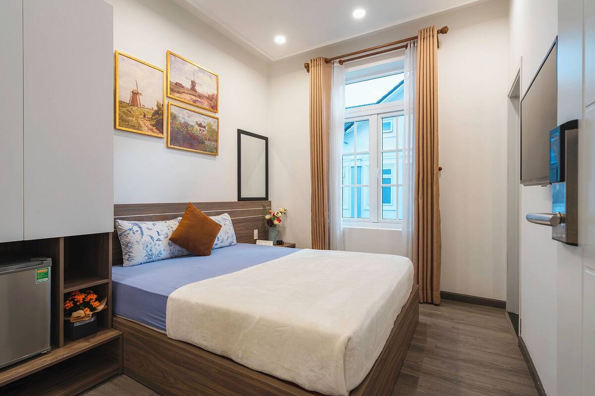 A hotel room with a bed, a TV, a wardrobe, and a window with curtains.